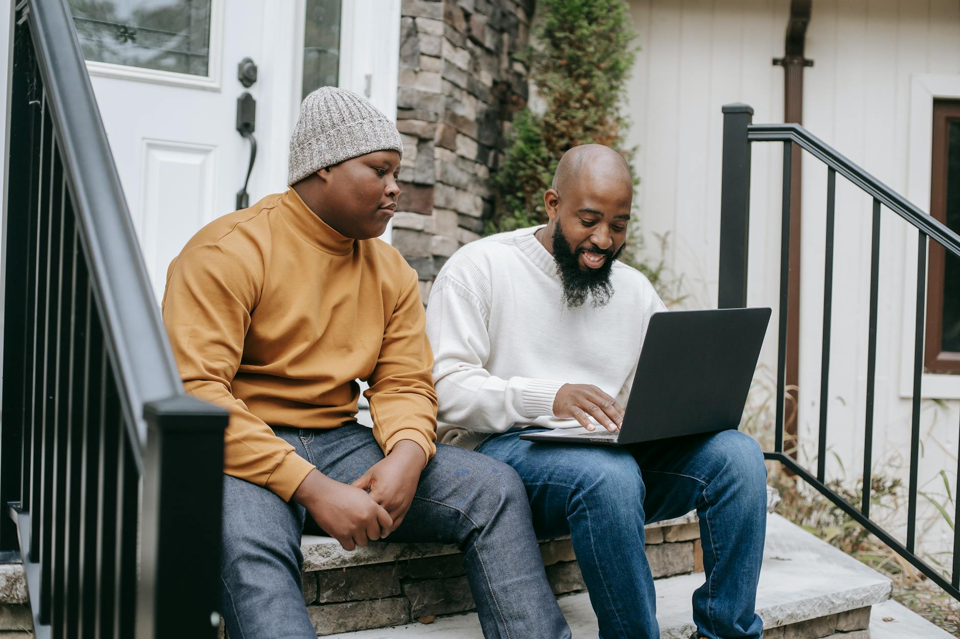 cheerful black businessman browsing laptop with son